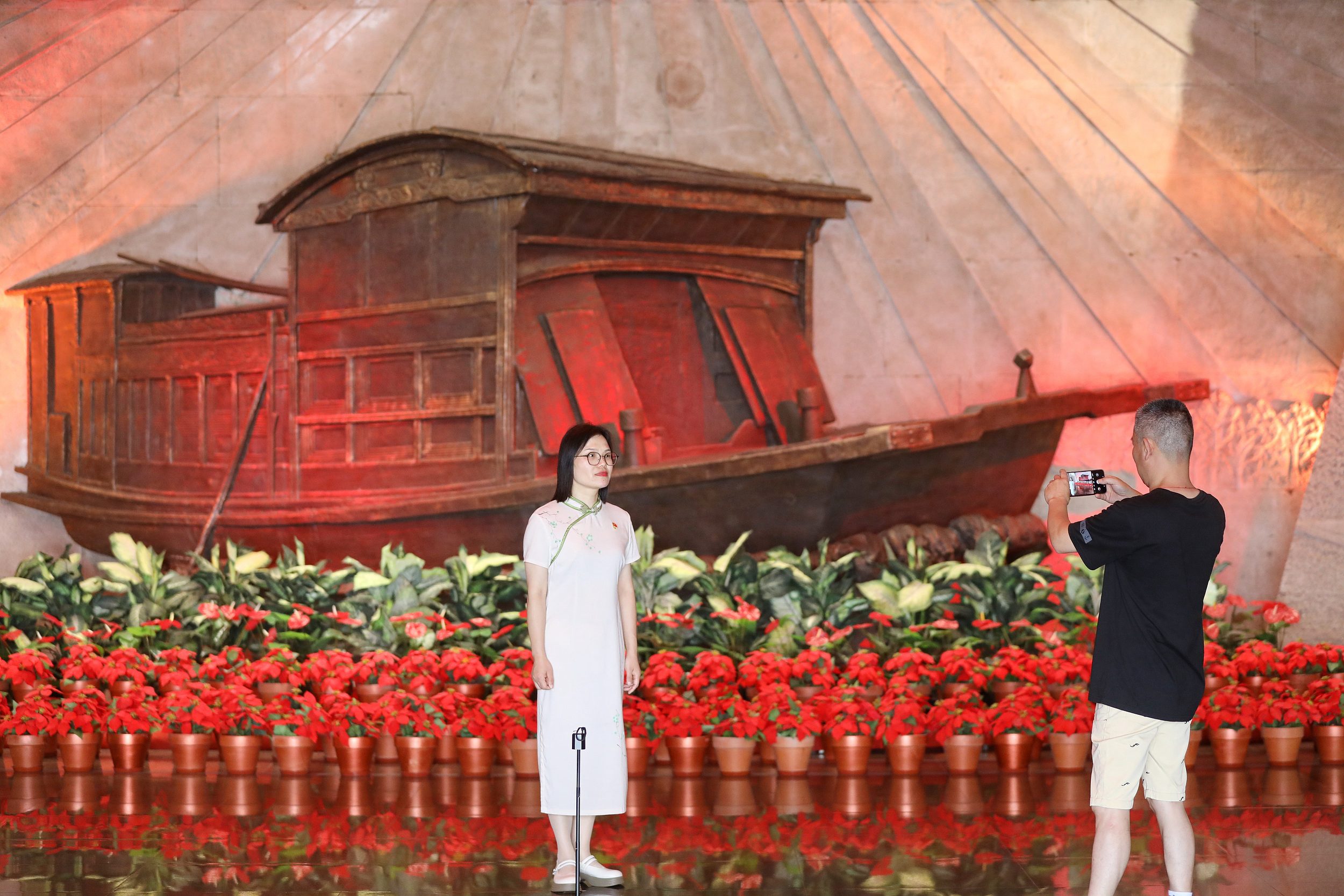 2025年6月24日，浙江嘉興，游客在南湖革命紀(jì)念館與紅船雕塑合影。（圖片來源：視覺中國）